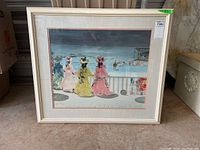 Front view of the framed print showing four women in vintage dresses looking over a beach scene beneath a moody sky.