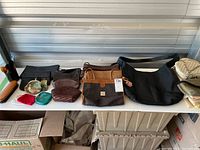 Wide shot showing several purses and coin purses arranged on a table as well as shoe care items.