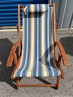 Full view of teak deck chair with blue, yellow, and white striped canvas fabric and wooden frame.