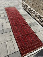 Full length view of Baluchi runner rug laid flat outdoors on stone paving