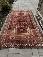 Full view of rug laid flat on stone pavers showing overall design and condition