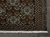 Close-up photo of the rug corner showing detailed geometric pattern and fringes.