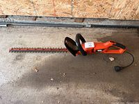 Full view of the Black & Decker electric hedge trimmer showing the cutting blade, loop handle, main handle, and power cord.