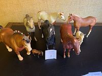 Photo showing the entire group of eight horse figurines on a black surface, different sizes and colors visible.