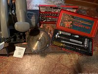 Photo showing all items: Craftsman circular saw, two metal socket sets with tools displayed on a surface.