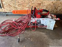 Electric chainsaw with bar cover, extension cord coiled, instruction manual and original box.