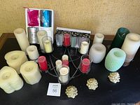 Overview of all flameless candles in various colors and sizes, decorative metal candle holder, Christmas tree decorations, and boxed candle holders placed on a black table against a beige background.