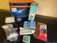 Photo displaying all items included: Linksys router, BlendJet blender, car charger, lint removal tool, pedometer, foot roller, and power chargers all new in boxes.