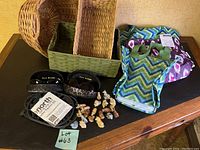 Photo of all home items on wooden table including three woven baskets, two pairs of Joan Rivers sunglasses in cases, ice traction shoe attachments, 20 small figurines, and three insulated shopping/lunch bags.