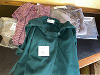 Photo showing four items: vintage Hourihan dark green wool cape, gray cape/duster, pink-purple sweater, taupe wrap.