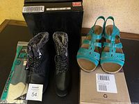 Photo of turquoise Clarks wide sandals, black waterproof insulated boots with faux fur lining, and a package of insoles placed beside their boxes.