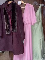 Photo showing the dark burgundy Jones New York winter coat with removable dark fur collar next to a floor-length pink dress and light green dress