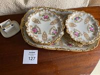 Photo of serving plate, salad plates stacked, and porcelain toothpick holder showing floral and gold decoration
