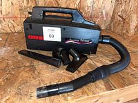 Photo of Oreck American Heritage XL hand vacuum with four attachments positioned in front of it on wooden surface.