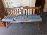 Solid wood bench showing overall front view and three blue cushions on the seat.