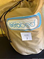 Drawstring carry bag with Aerobed branding and MaxSold lot label, containing twin size air mattress and accessories.