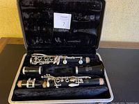 Vintage Bundy clarinet pieces arranged inside original black velvet-lined case, showing all four main parts separated and fitted into compartments.