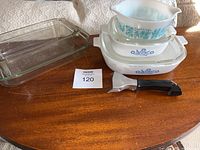 Full set of vintage baking items including Pyrex and CorningWare dishes, a metal tool, and loaf pan.