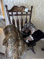 Rocking chair with two animal print fuzzy throws draped over it, showing textile patterns and texture.