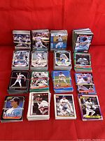 Front view showing multiple stacks of baseball cards from various sets arranged on red fabric background. Visible player images and card fronts include chrome and glossy finishes.