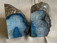 Pair of blue agate bookends shown upright on beige fabric background, showcasing natural polished and rough textures of the stones.