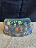 Front and angled view of Disney Store Finding Nemo & Friends 10-piece figurine set in original clear plastic packaging with Nemo branded base.