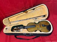 Full view of violin inside an open hard case, showing violin body and bow in case.