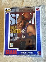 Front view of Vince Carter Funko POP! inside Slam Magazine cover style collectible box, showing Vince Carter in a Raptors jersey with a basketball behind him and the box labeled number 03.