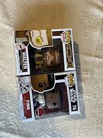 Two Funko POP figures in box: Walter #82 and Finn #76 laying side by side on a textured surface.