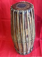 Front view of the Mridangam drum showing the wooden barrel shell and vertical tension ropes.