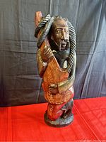 Front and side views of the hand carved wooden Rasta man playing guitar sculpture showing detailed carving, painted accents, and braided hair.