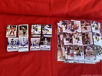 Top-down view of multiple stacks of NHL hockey cards arranged on a red surface showing various players and teams primarily from Topps and Upper Deck, spanning vintage to modern.