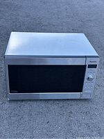 Front view of Panasonic stainless steel microwave with black glass door and control panel on the right side.