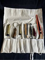 Photo showing 8 of the pumpkin carving tools and canvas organizer pouch, arranged for display.