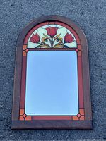 Full view of the vintage 22x14 wall mirror showing the wooden frame with stained glass style tulip and geometric starforms design at the top and clear mirror below.