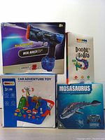 Photo showing the electric water gun box, LCD doodle board packaging, car adventure toy box, and RC Mosasaurus toy box