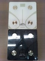 Two Renpho smart body fat scales, one white and one black, both new and wrapped in plastic.