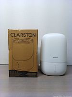 Clarston humidifier and its original cardboard boxed next to it, white matte finish, minimalist design