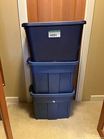 Stack of three blue Rubbermaid storage bins with a label on the top bin