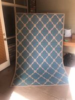 Blue and white geometric outdoor rug hanging indoors.