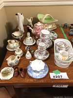 Photo showing multiple fine china items including teacups, teapots, creamer, figurines, and decorative ceramics.