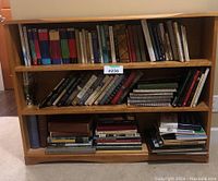 Wide photo showing full bookshelf with three shelves filled with books and novels.