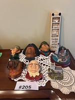 Overview of all Bossons character bust plaques, dog bust, carved decorative sign, and miniature dioramas arranged on table.