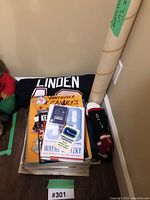 Vancouver Canucks hockey scrapbooks partially visible beneath mini Linden jersey and commemorative posters in rolled tubes