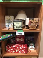 Shelf with multiple home decor and Christmas decoration items including lamp, tins, stamps basket, gift boxes and glass globe.