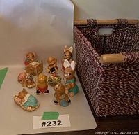 Side view of all 10 figurines arranged and next to woven basket