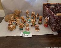 Image shows the entire collection of 15 animal figurines including a large ceramic dog and various rabbits arranged on white background next to a woven basket.