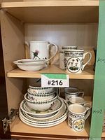 Overall view of top and bottom cabinet shelves showing pitcher, mugs, plates and bowls