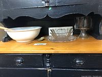 Photo showing a white Royal Ironstone bowl with wooden spoon, a cut glass bowl with plate, silver spoon, and dark pedestal bowl all on a wooden surface.