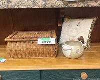 Front view of rectangular wicker sewing basket next to cushion and ceramic yarn holder